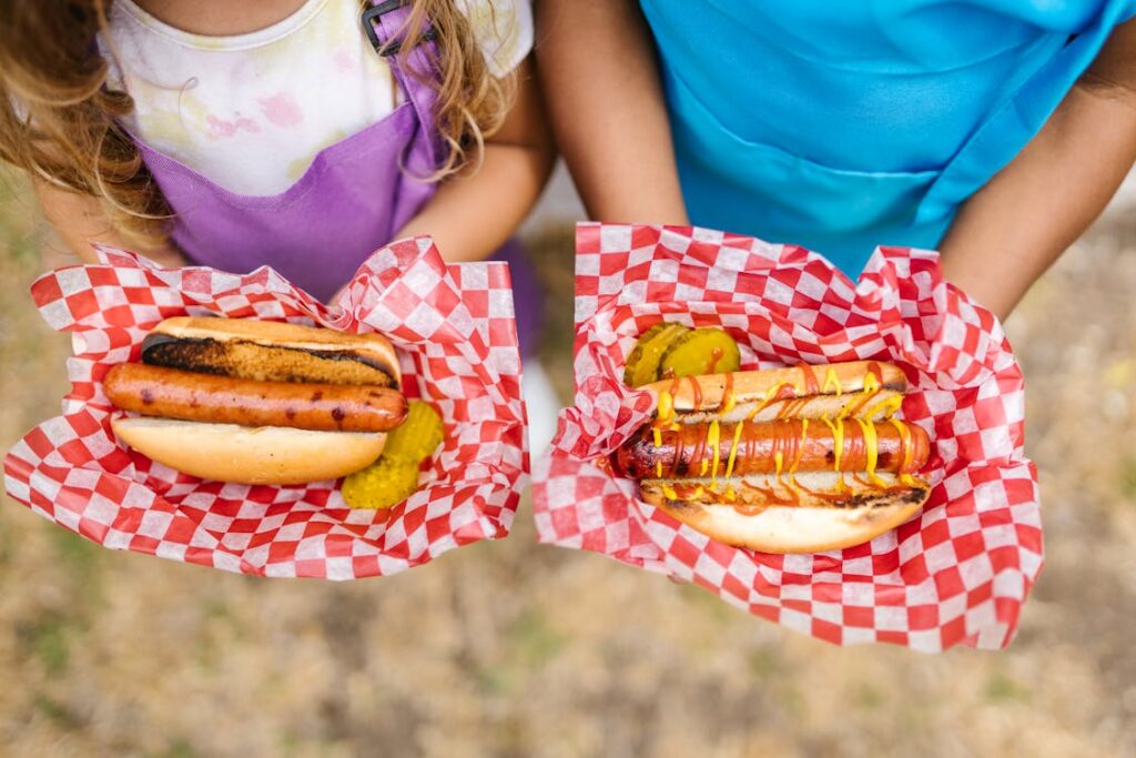 kids holding two hot dogs.