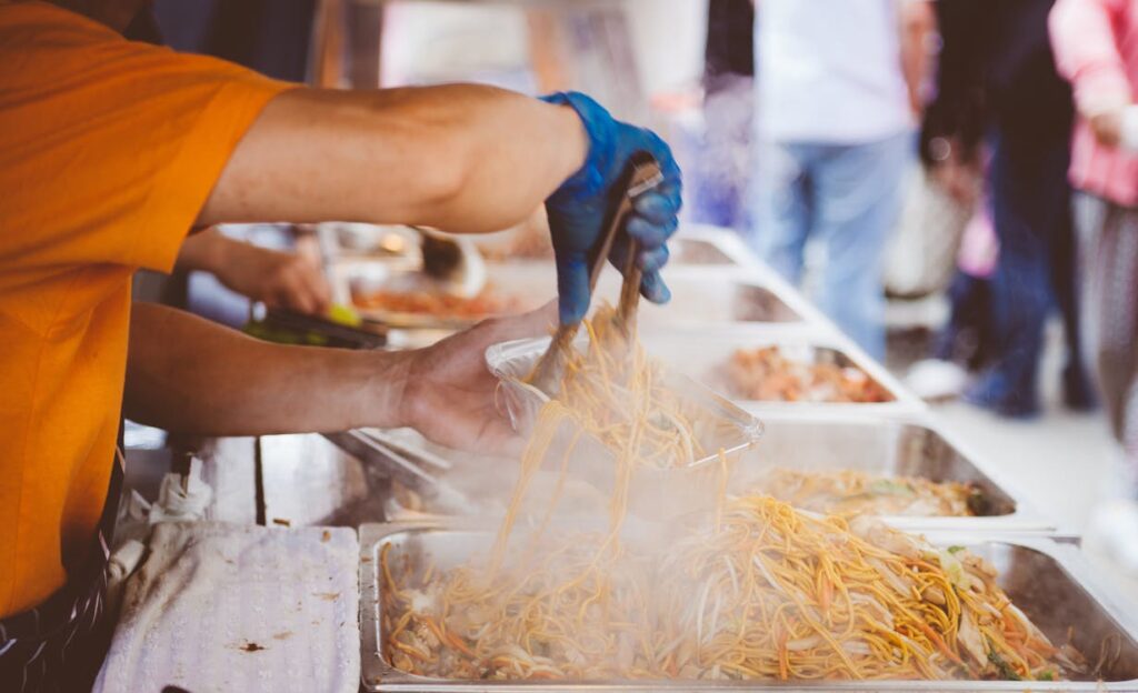a person dishing out noodles.