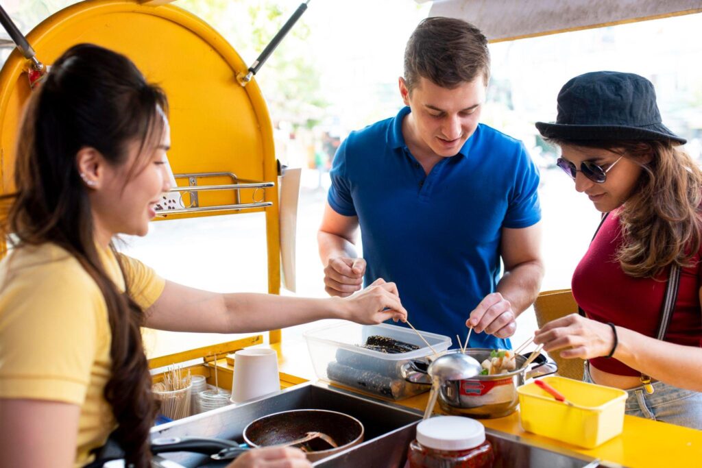 a couple wearing a red and blue shirt at a food cart testing samples