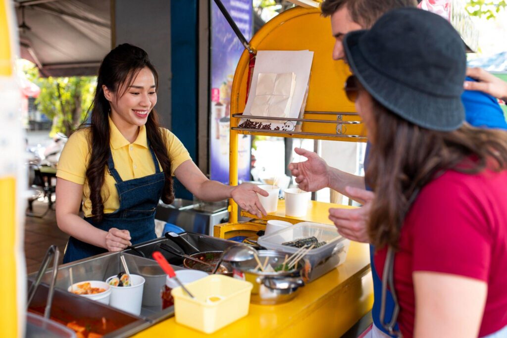 a food cart employee wearing a yellow shirt serving food to customers