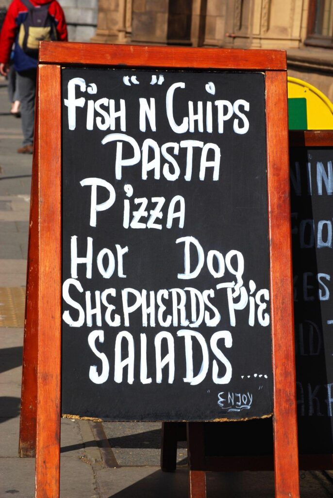 a chalkboard with a menu written on it, placed on the side of a food stall