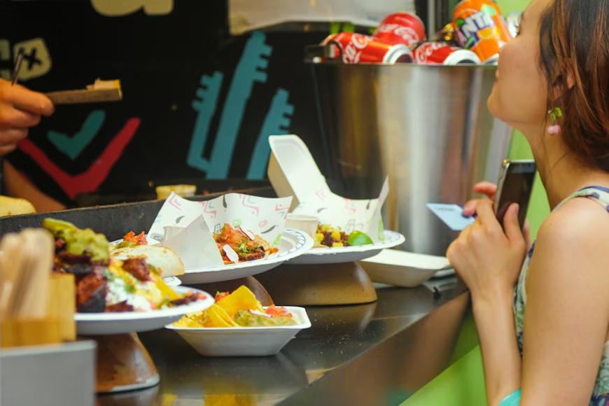 a food vendor serving food on paper plates to a happy customer