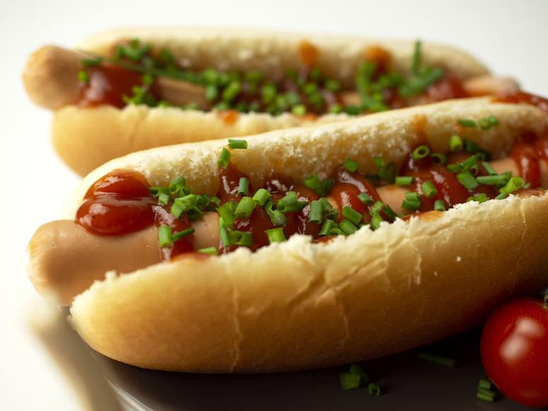 close-up of two hot dogs with ketchup and spring onion as toppings on them