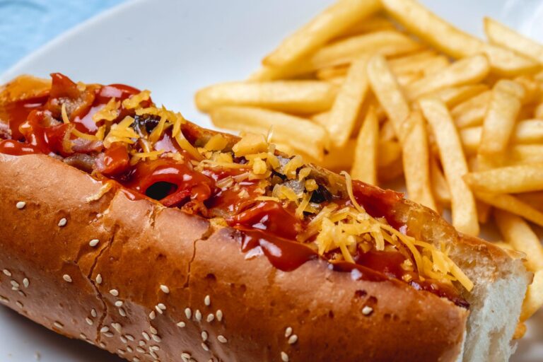 close-up of a loaded hot dog with fries on the side