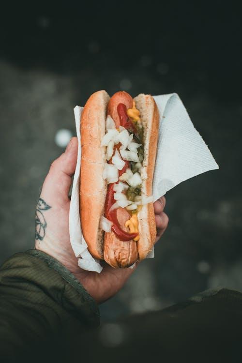 a closeup shot of an idnidviual holding a hotdog