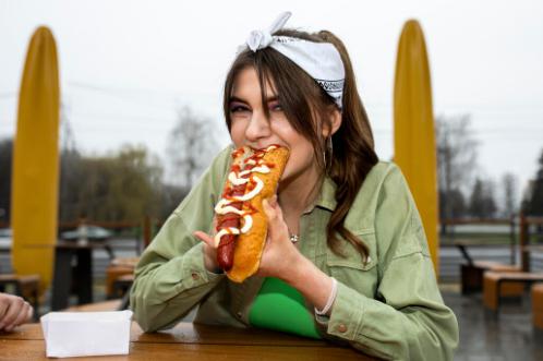 a woman eating a loaded hotdog