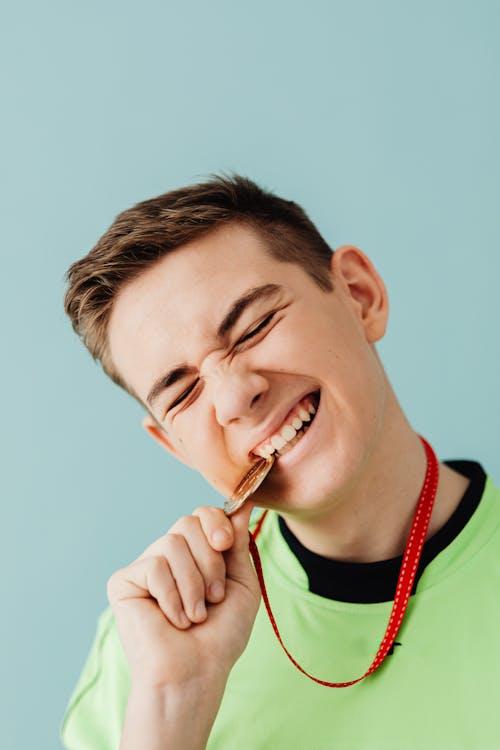 a young boy biting their gold medal