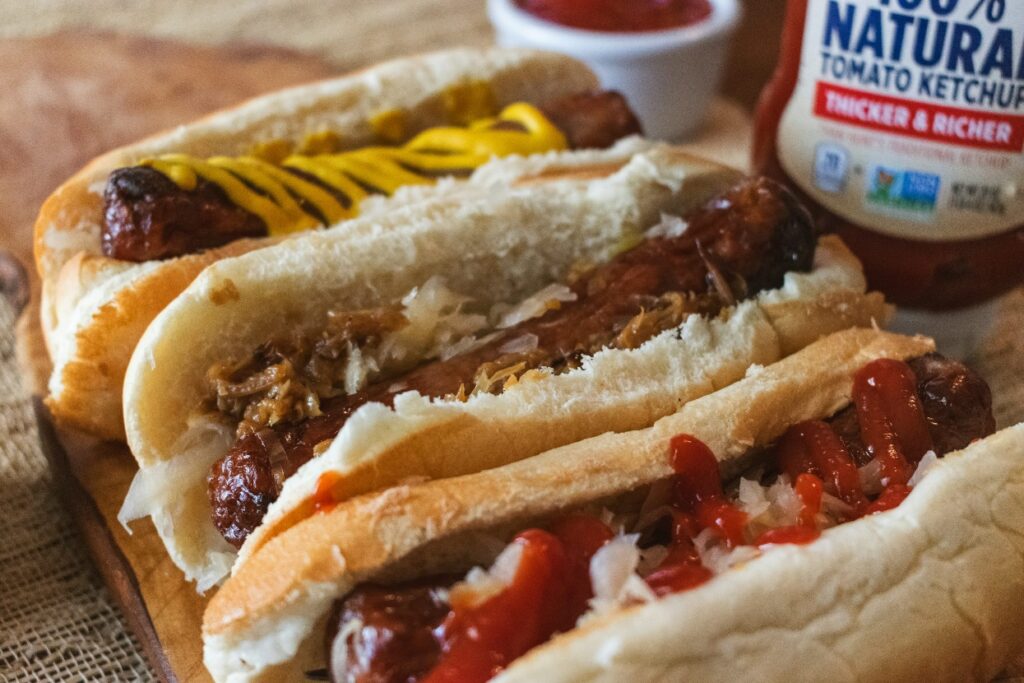 Classic American-style hot dogs with ketchup, mustard, and sauerkraut on a rustic table